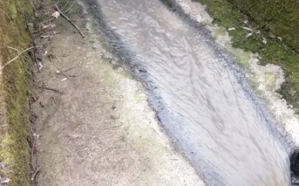 Zrzut ścieków koloru szarego do rzeki z betonowego odpływu