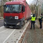 Kontrola czerwonej ciężarówki z odpadami. Funkcjonariusz służby celno-skarbowej